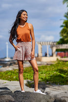 Woman wearing rust and white shorts and rust color tank top.